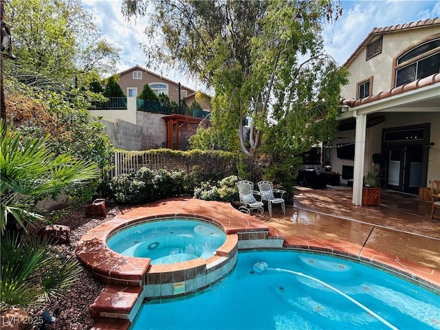 view of swimming pool with a pool with connected hot tub, fence, and a patio