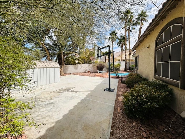 view of patio featuring a fenced backyard, a storage unit, a fenced in pool, and an outdoor structure