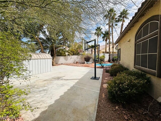view of patio / terrace featuring an outdoor structure, a fenced backyard, and a shed
