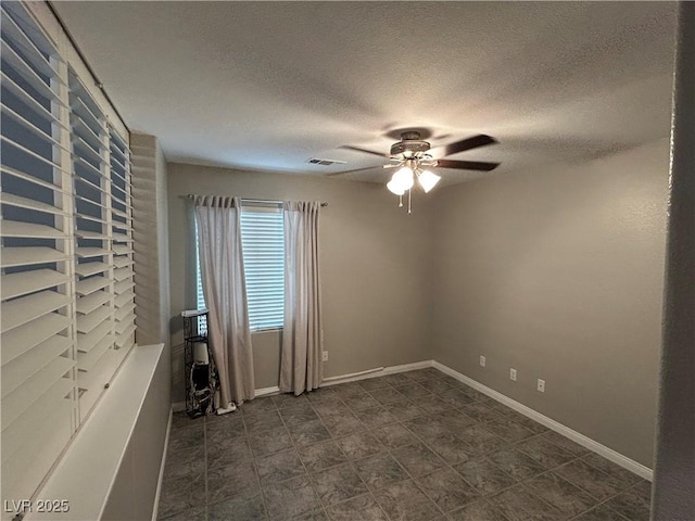 empty room with visible vents, a ceiling fan, a textured ceiling, and baseboards