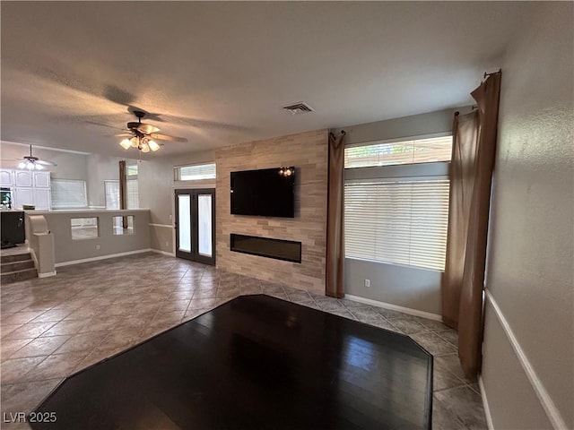 unfurnished living room featuring tile patterned floors, visible vents, a healthy amount of sunlight, and a tile fireplace