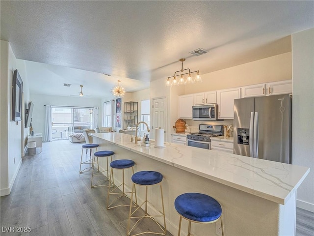 kitchen with white cabinetry, appliances with stainless steel finishes, open floor plan, and dark wood finished floors