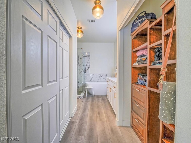 hallway featuring visible vents and light wood finished floors