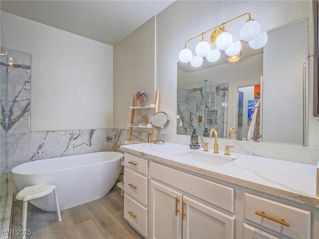 bathroom with a freestanding bath, wood finished floors, a marble finish shower, and vanity