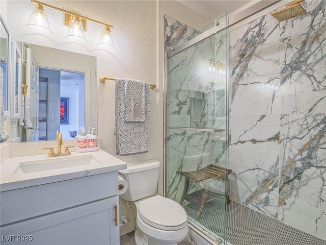 full bath featuring a textured wall, vanity, a marble finish shower, and toilet