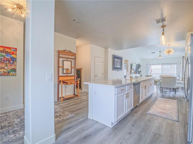 kitchen featuring visible vents, light wood-style floors, white cabinetry, appliances with stainless steel finishes, and a center island with sink