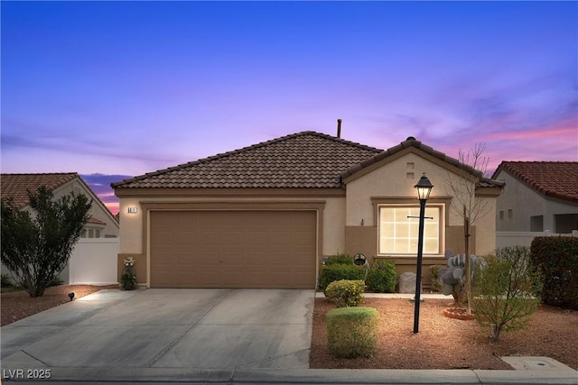 view of front of home featuring stucco siding, concrete driveway, an attached garage, fence, and a tiled roof