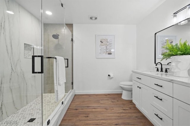 full bathroom featuring toilet, wood finished floors, vanity, baseboards, and a marble finish shower