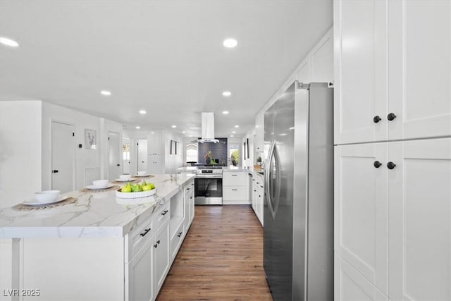 kitchen with stove, island exhaust hood, freestanding refrigerator, and white cabinets