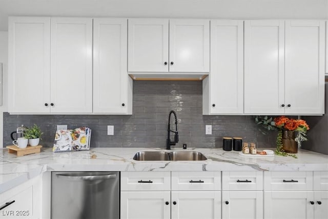 kitchen featuring tasteful backsplash, stainless steel dishwasher, white cabinetry, a sink, and light stone countertops