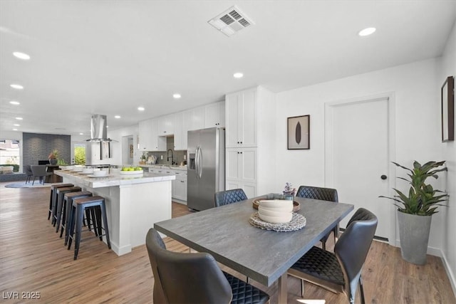 dining space featuring light wood-style floors, recessed lighting, visible vents, and baseboards