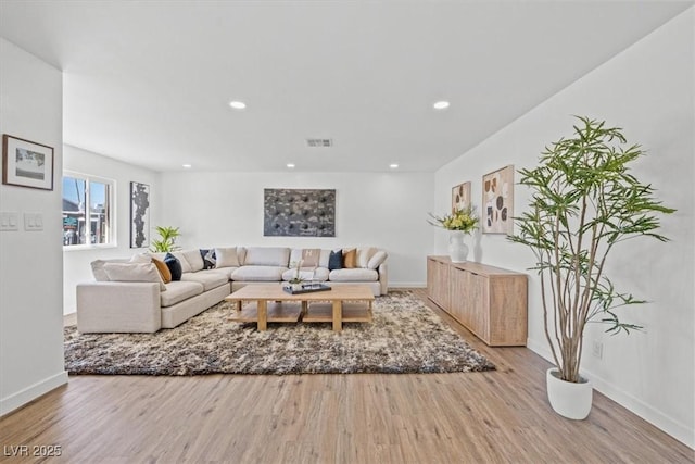 living room featuring baseboards, visible vents, wood finished floors, and recessed lighting