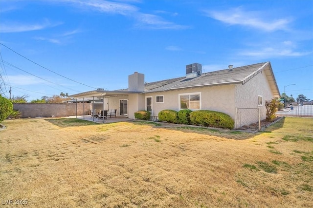 rear view of house featuring a patio, central air condition unit, fence, a lawn, and stucco siding