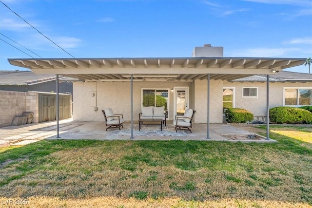 rear view of house with a lawn, a patio area, and stucco siding