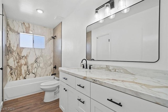 bathroom featuring toilet, vanity, wood finished floors, and shower / tub combination