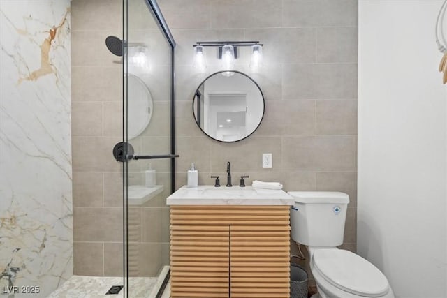 bathroom with toilet, tile walls, tiled shower, and vanity