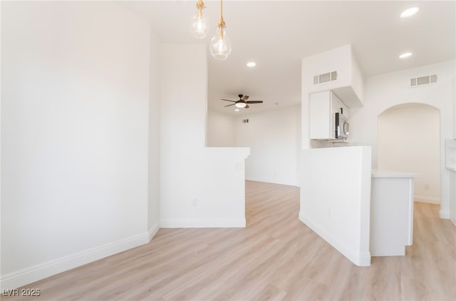 spare room with light wood finished floors, visible vents, arched walkways, and recessed lighting