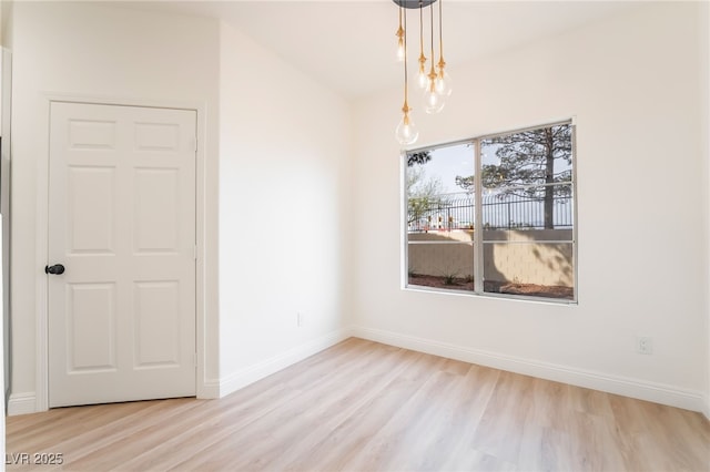 unfurnished dining area with a notable chandelier, baseboards, and wood finished floors