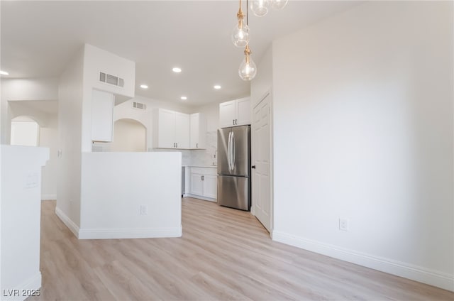 kitchen featuring light wood finished floors, white cabinetry, visible vents, and freestanding refrigerator