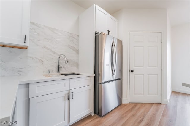 kitchen with light wood-style flooring, a sink, white cabinets, light countertops, and freestanding refrigerator