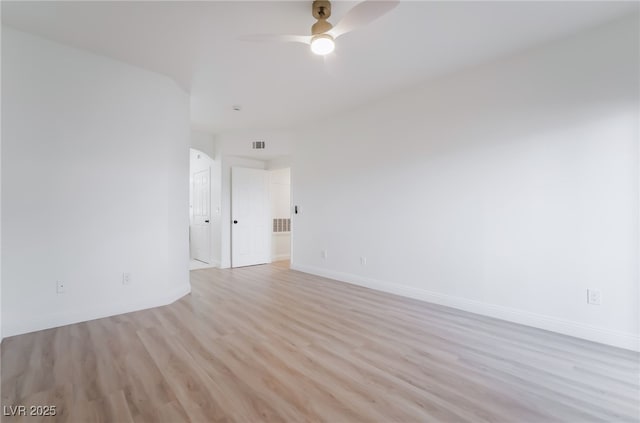 empty room featuring visible vents, a ceiling fan, light wood-style flooring, and baseboards