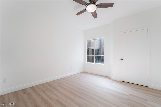 empty room with ceiling fan, light wood-type flooring, and baseboards