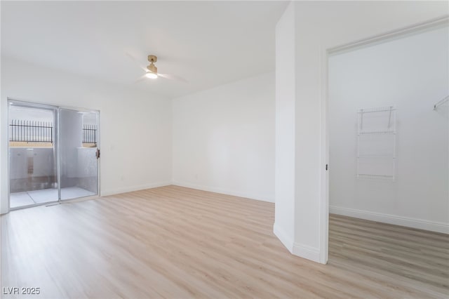 empty room with a ceiling fan, light wood-style flooring, and baseboards