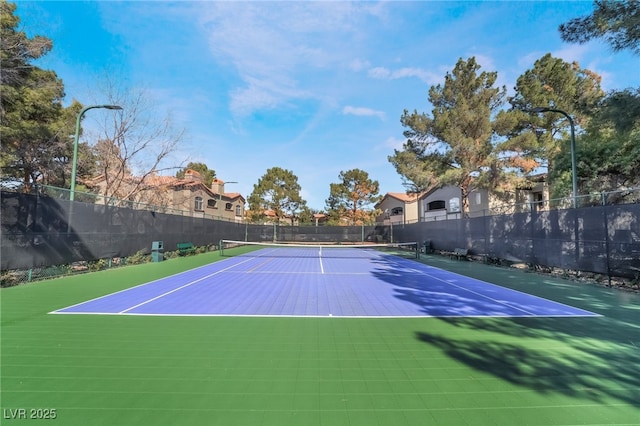 view of tennis court featuring community basketball court and fence