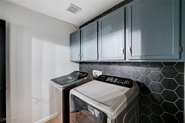 clothes washing area with independent washer and dryer, cabinet space, and visible vents