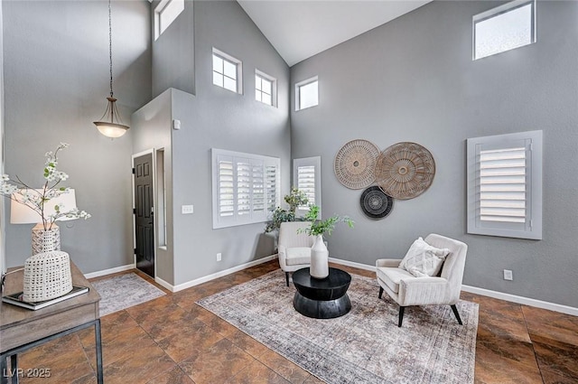 sitting room with baseboards, a high ceiling, and stone finish floor