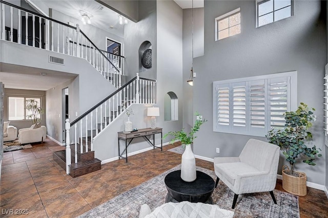 living area with stairway, baseboards, visible vents, and a wealth of natural light