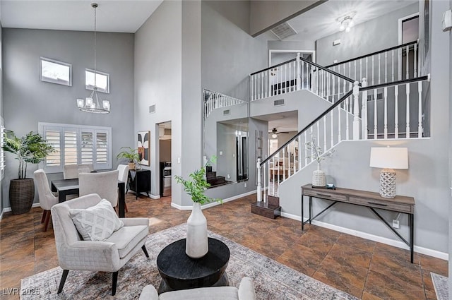 living area with visible vents, baseboards, an inviting chandelier, and stairs