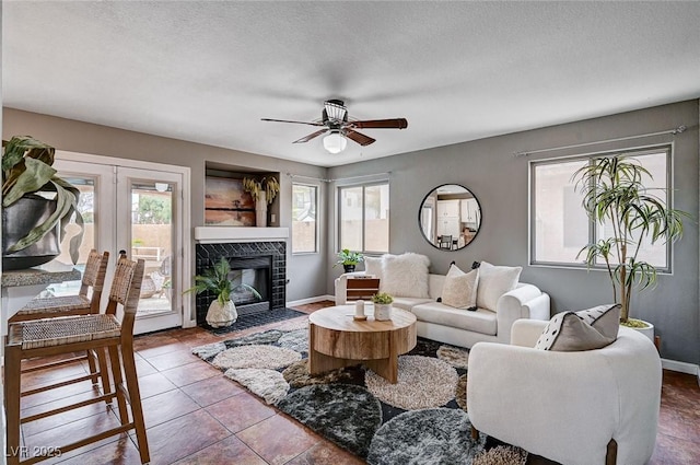 living area featuring baseboards, a healthy amount of sunlight, and a tiled fireplace