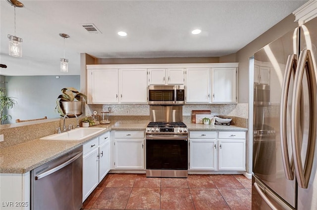 kitchen featuring a sink, white cabinetry, appliances with stainless steel finishes, a peninsula, and decorative backsplash