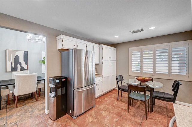 kitchen featuring visible vents, freestanding refrigerator, light countertops, white cabinets, and a chandelier