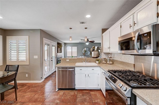 kitchen with visible vents, light countertops, a peninsula, stainless steel appliances, and a sink