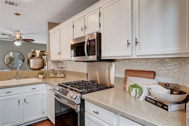 kitchen with a sink, visible vents, appliances with stainless steel finishes, and white cabinetry