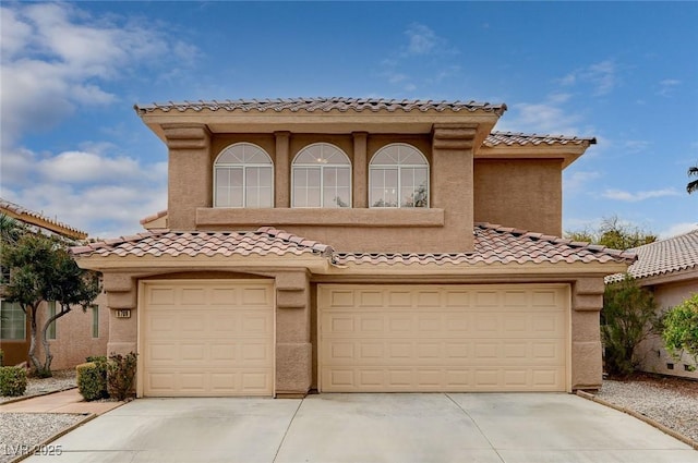 mediterranean / spanish home with a tiled roof, a garage, driveway, and stucco siding