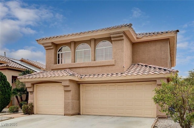 mediterranean / spanish-style house with stucco siding, driveway, an attached garage, and a tile roof