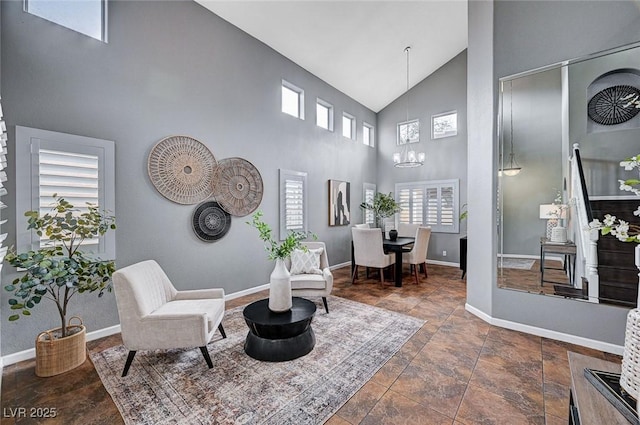 living area featuring baseboards, high vaulted ceiling, and an inviting chandelier