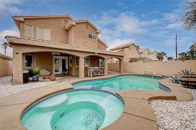 back of house featuring a fenced backyard, a pool with connected hot tub, stucco siding, french doors, and a patio area