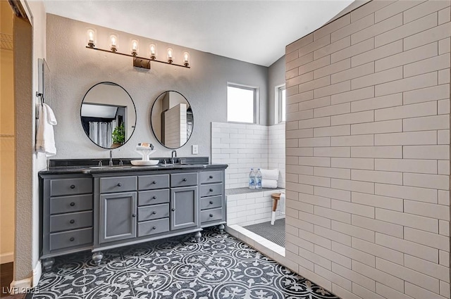 bathroom featuring double vanity, tile patterned flooring, walk in shower, and a sink