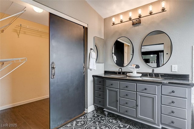 bathroom featuring a sink, baseboards, wood finished floors, and double vanity