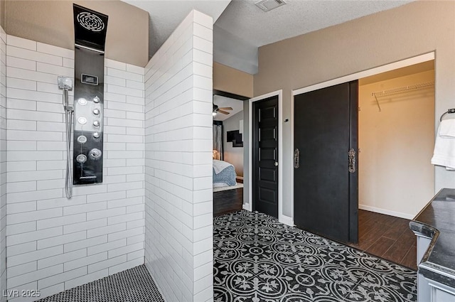 full bath featuring visible vents, baseboards, ceiling fan, tiled shower, and ensuite bathroom