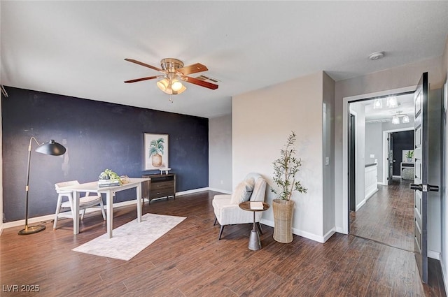 sitting room featuring baseboards, a ceiling fan, wood finished floors, and an accent wall