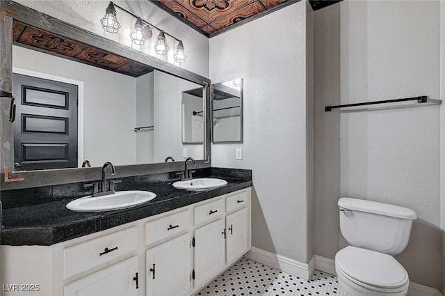 full bath featuring double vanity, toilet, baseboards, and a sink