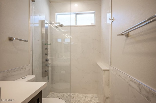 bathroom with a textured wall, a shower stall, toilet, and vanity