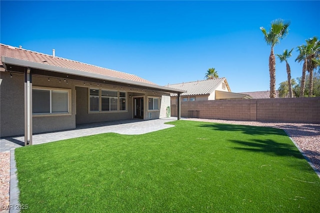 back of property with stucco siding, a fenced backyard, a patio, and a lawn