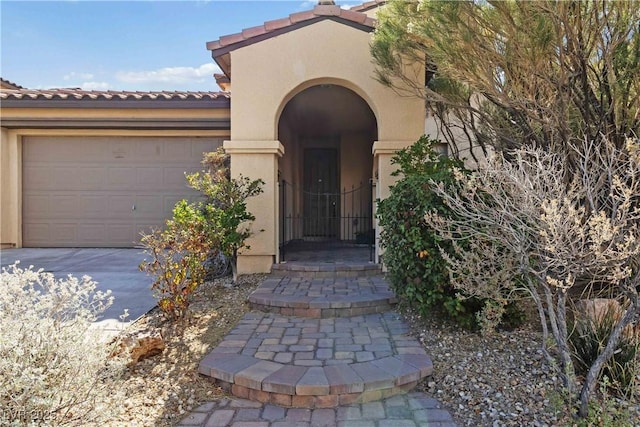 doorway to property with stucco siding, a tiled roof, concrete driveway, and a garage