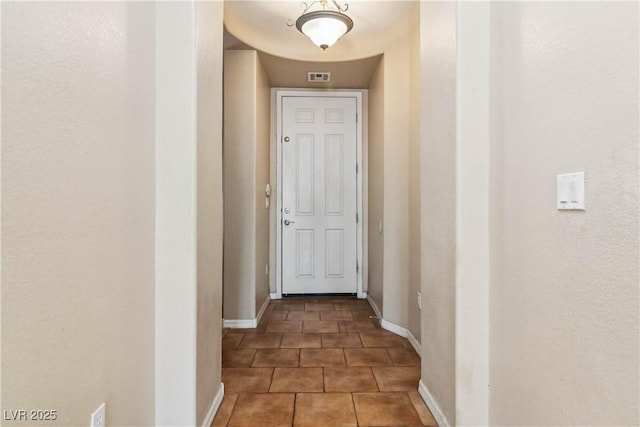 hallway featuring tile patterned floors, visible vents, and baseboards